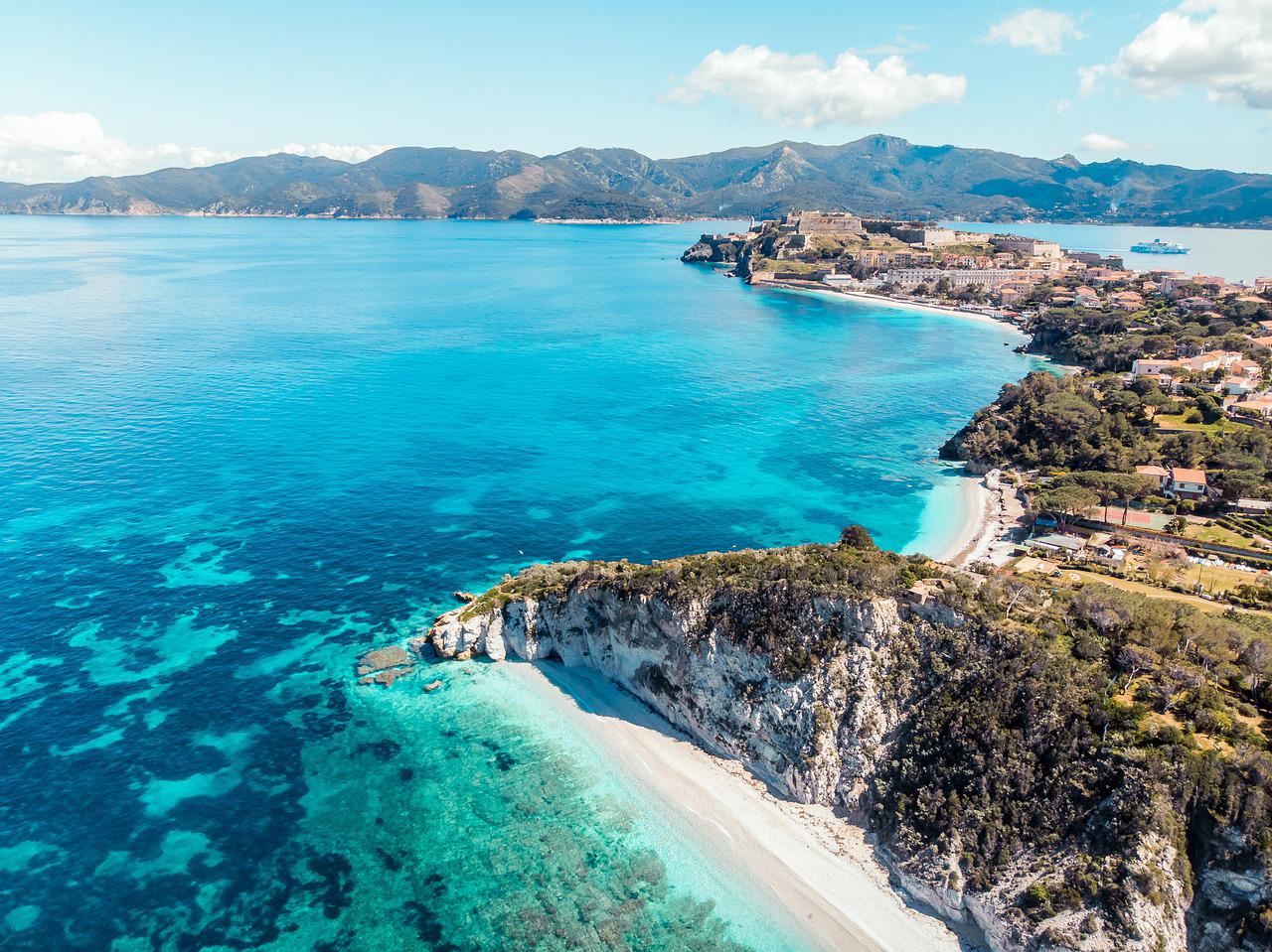 Vista aerea dell'Isola d'Elba con acque turchesi, spiaggia bianca e profilo costiero